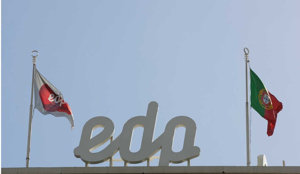 The flags of Energias de Portugal, (left), and Portugal fly above EDP’S headquarters in Lisbon. Photo: Bloomberg
