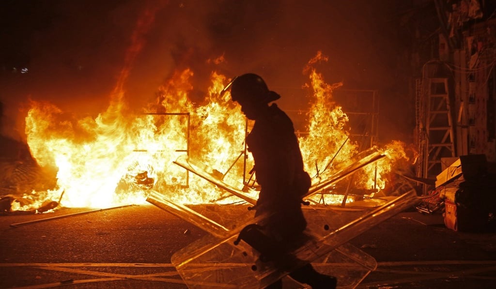 A police officer walks past a fire set by rioters in Mong Kok. Photo: AP