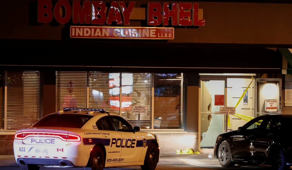 A police car parked outside the shattered glass doors of the Bombay Bhel restaurant. Photo: Reuters