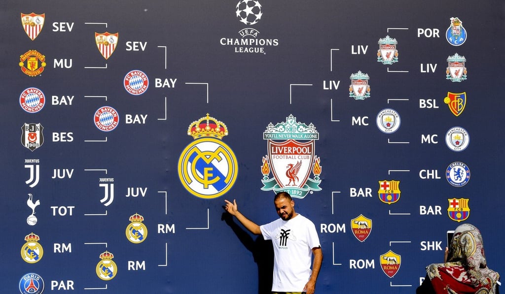 Fans pose for a photograph in front of a banner charting each teams’ progress through the knockout stages of the Champions League. Photo: EPA