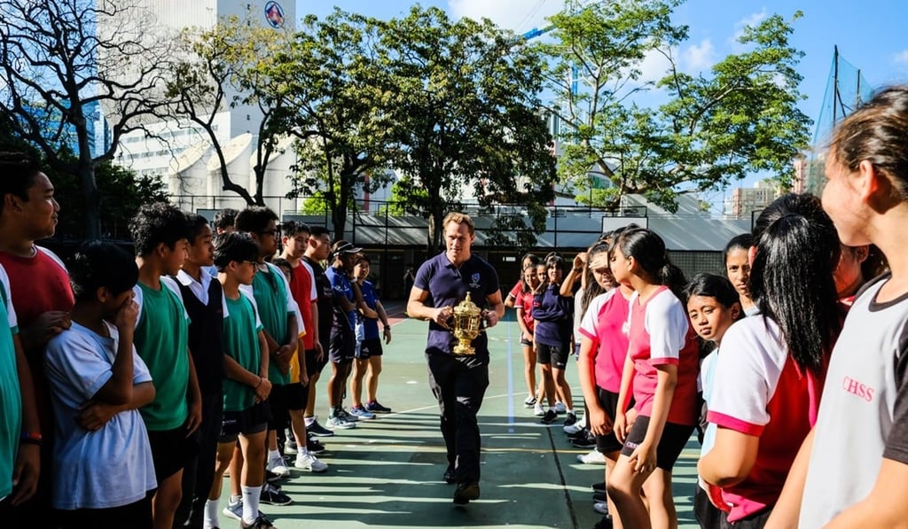 Josh Lewsey presents the Webb Ellis Cup to students from Confucius Hall Secondary School.