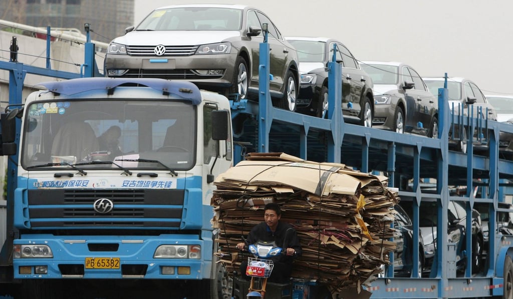 A man rides an electric tricycle past a truck loaded with new Volkswagen cars on a street in Nanjing. Photo: Reuters