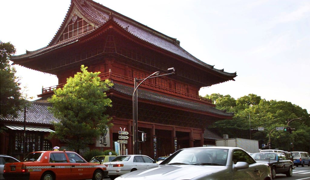 A car drives past one of Japan’s many Buddhist temples, in Tokyo. Many temples are said to be considering opening their doors for accommodation after the government changed laws. Photo: Reuters