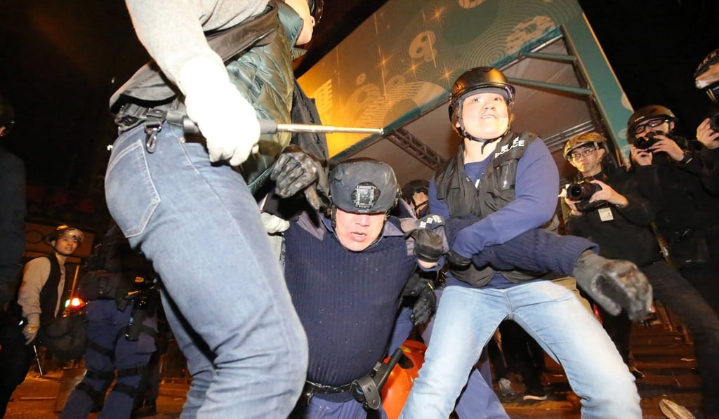 A police officer is helped by colleagues after being beaten up by rioters in Mong Kok on February 9, 2016. Photo: SCMP/ Edward Wong