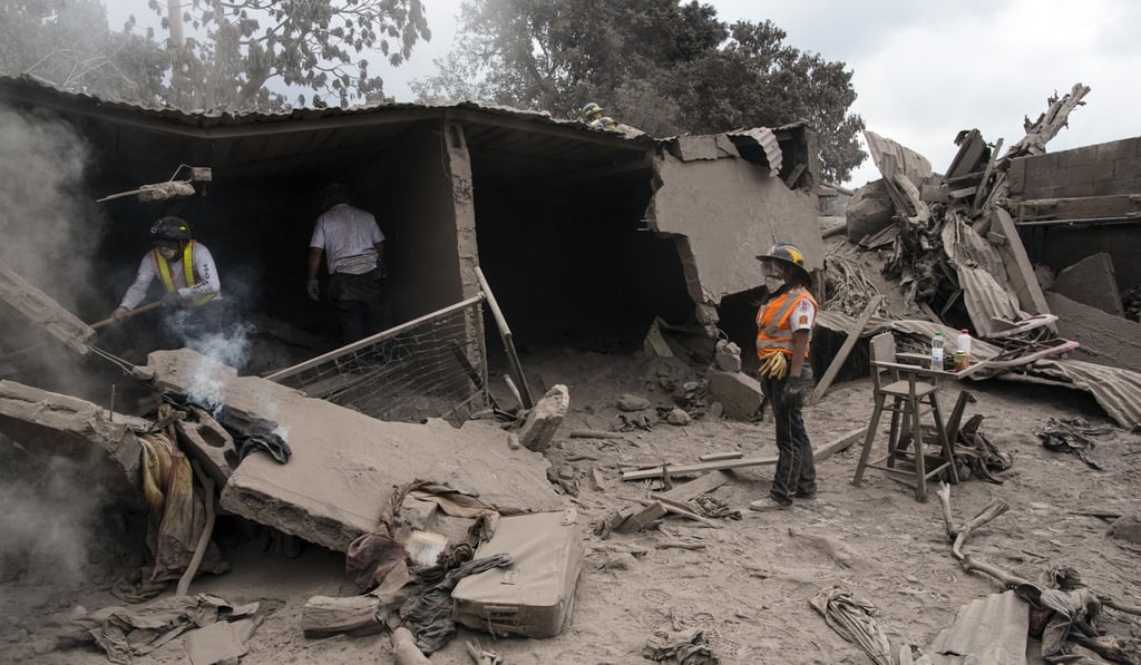 Firefighters search a home in the disaster zone near the Volcan de Fuego, in Escuintla, Guatemala, on Tuesday. Photo: AP