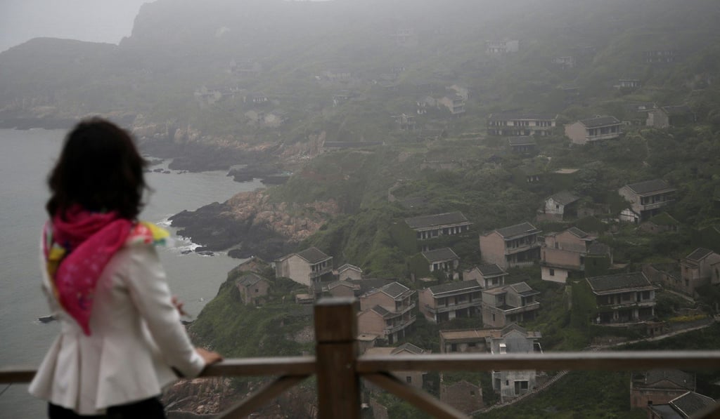 A tourist gazes out across Houtouwan as mist rolls in from the sea. Photo: AP A tourist gazes out across Houtouwan as mist rolls in from the sea. Photo: AP