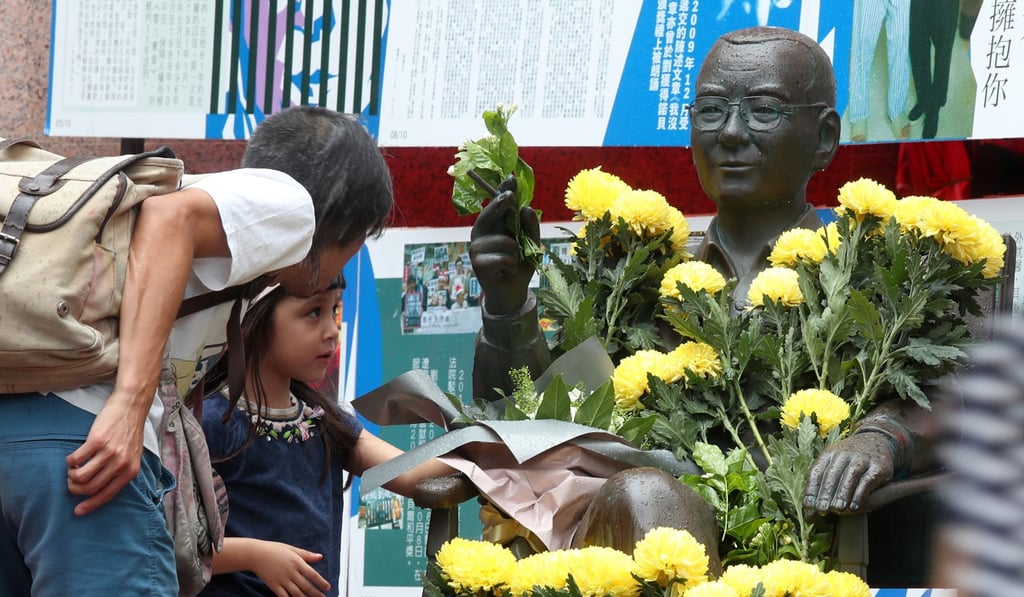 A child places a flower on the statue of Liu Xiaobo in Times Square. Photo: K.Y. Cheng