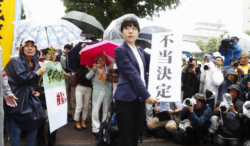 A lawyer holds a banner that reads ‘unjust ruling’ outside the Tokyo High Court. Photo: Kyodo