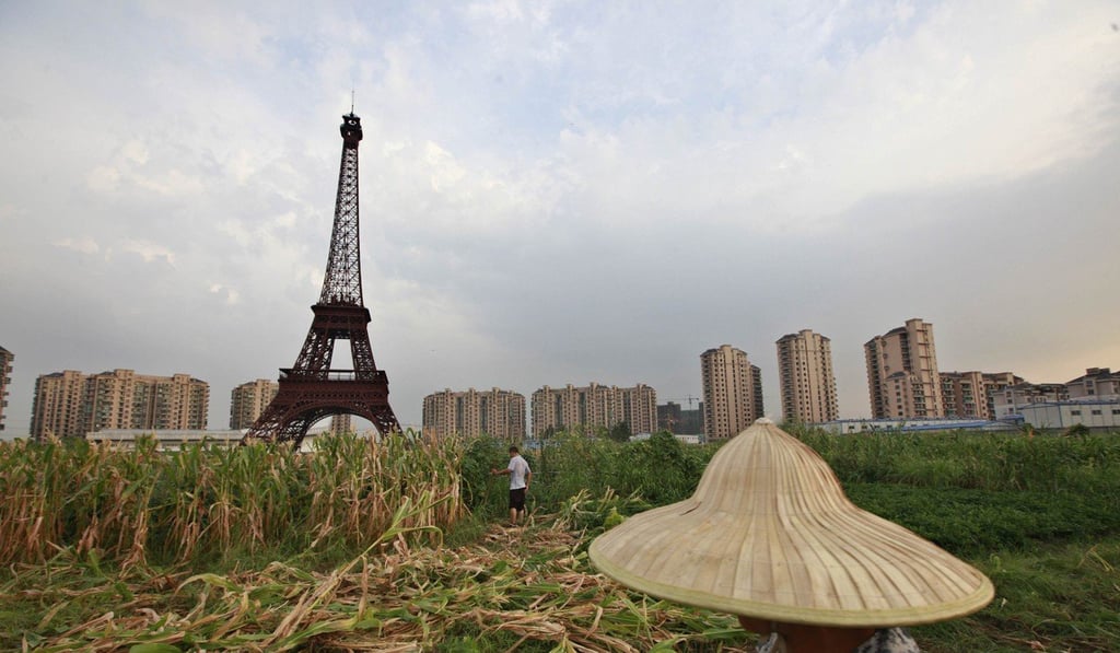 A farmer walks through a corn field near a replica of the Eiffel Tower that forms part of the Tianducheng development in Hangzhou, Zhejiang province. Photo: Reuters
