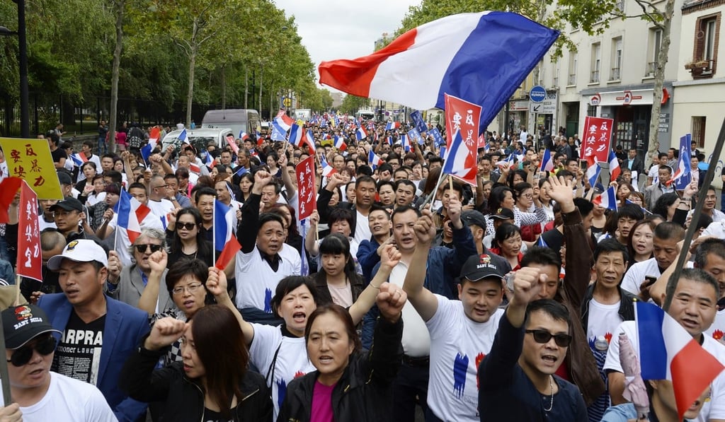 People wave French flags as they march during a demonstration in Paris on August 21, 2016, organised by the Chinese community after the death of Zhang Chaolin. Photo: AFP