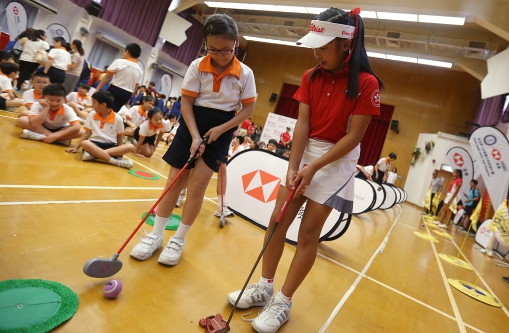 Young golfing star Arianna Lau (right) lends her expertise to a fellow student.