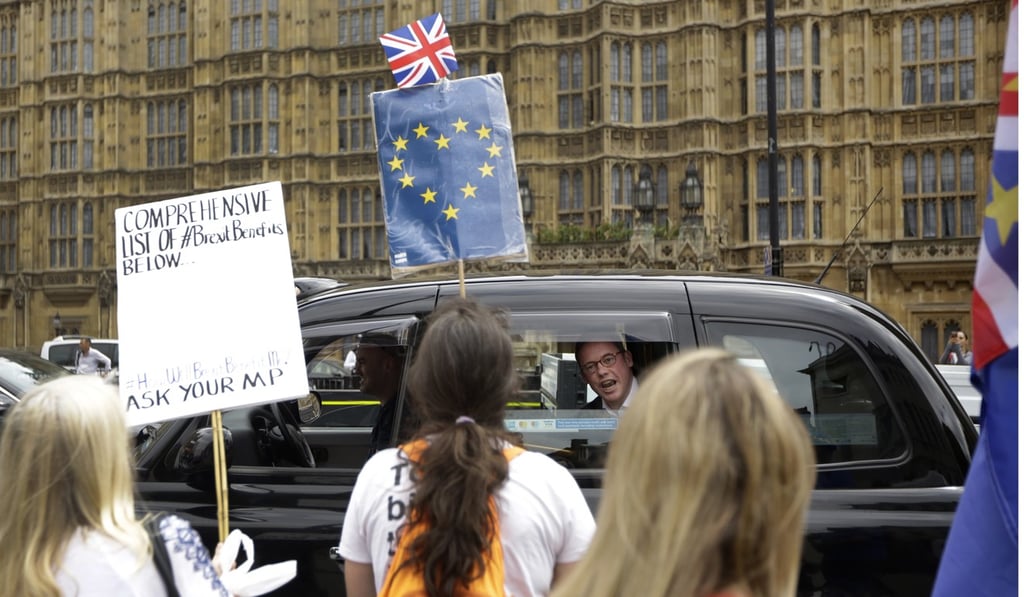A man in a passing taxi tells anti-Brexit, pro-EU protesters what he thinks of their demonstration. Photo: AP