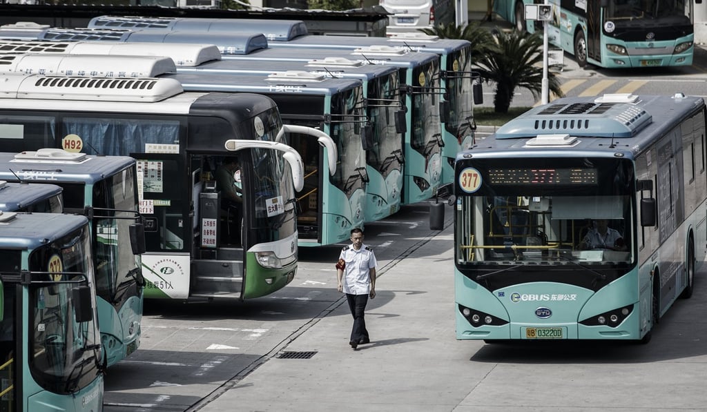 A worker walks past a row of electric buses in Shenzhen. Photo: Bloomberg