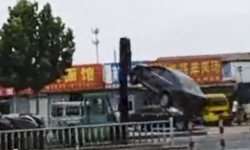 A black car dangles from a forklift truck after being carried along the road then dumped on a line of parked cars during the fatal rampage. Photo: Bjnews.com.cn