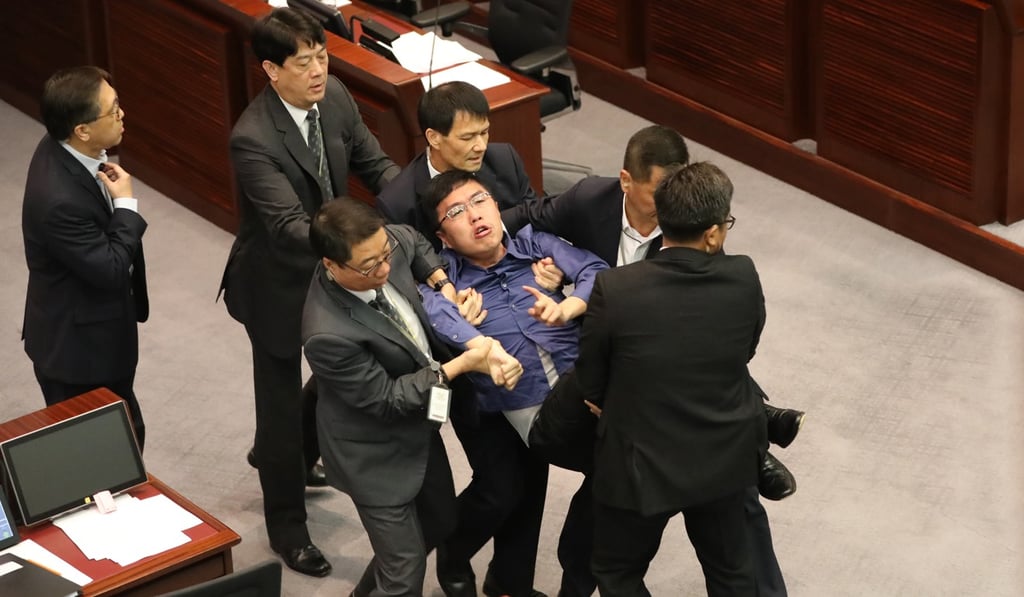 Security personnel carry pro-democracy lawmaker Au Nok-hin out of the Legislative Council during the Bill Committee's meeting on the controversial co-location bill. Photo: Edward Wong