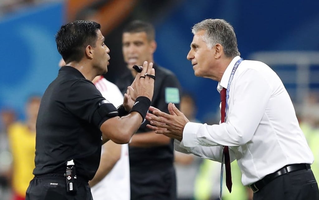 Referee Enrique Caceres talks to Iran coach Carlos Queiroz. Photo: EPA