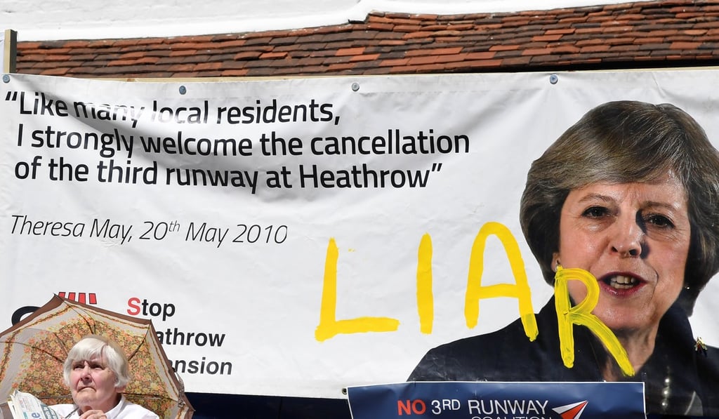 A woman sits in front of a protest banner against the expansion of Heathrow airport in the village of Harmondsworth, which is adjacent to the airport, on Monday. Photo: Reuters