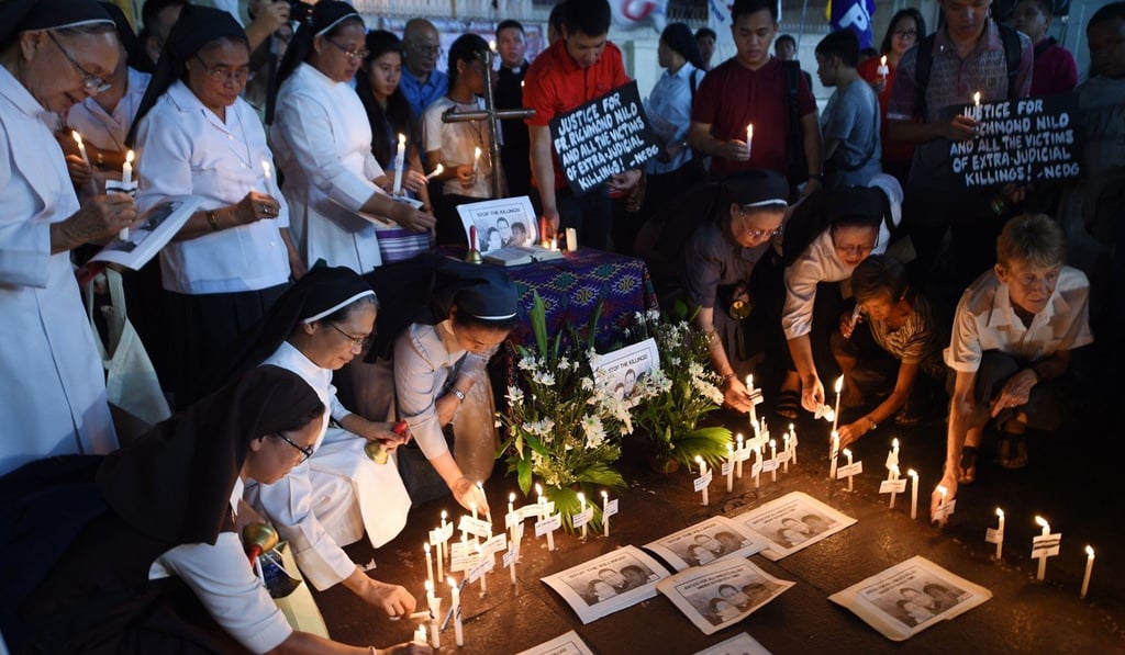 Australian nun Sister Patricia Fox (right, in white shirt), holds a candle along with colleagues as she attends a prayer vigil for murdered Catholic priests in front of Quiapo church in Manila on June 18. The Catholic Church has substantial support in the Philippines. Photo: AFP