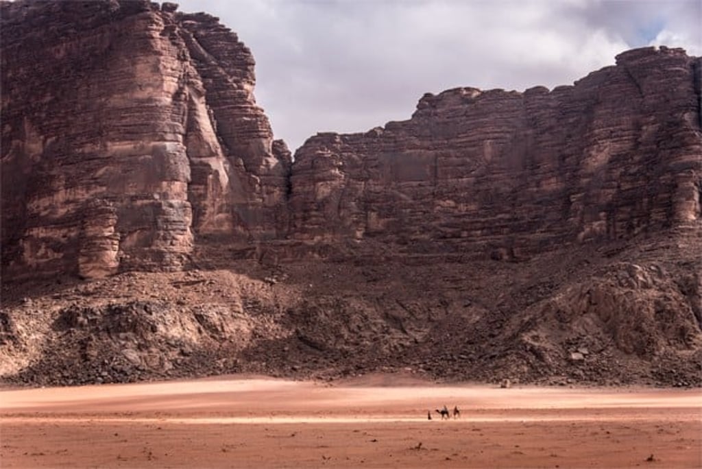 Local Bedouins riding camels through the desert landscape of Wadi Rum. Photo: NurPhoto
