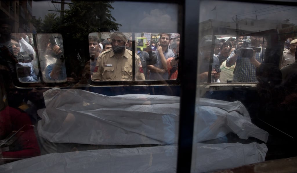An ambulance carries one of the 11 bodies found in Burari village, north Delhi, India. Photo: AP