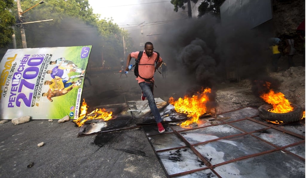 A man runs past a burning barricade in Port-au-Prince. Photo: AP