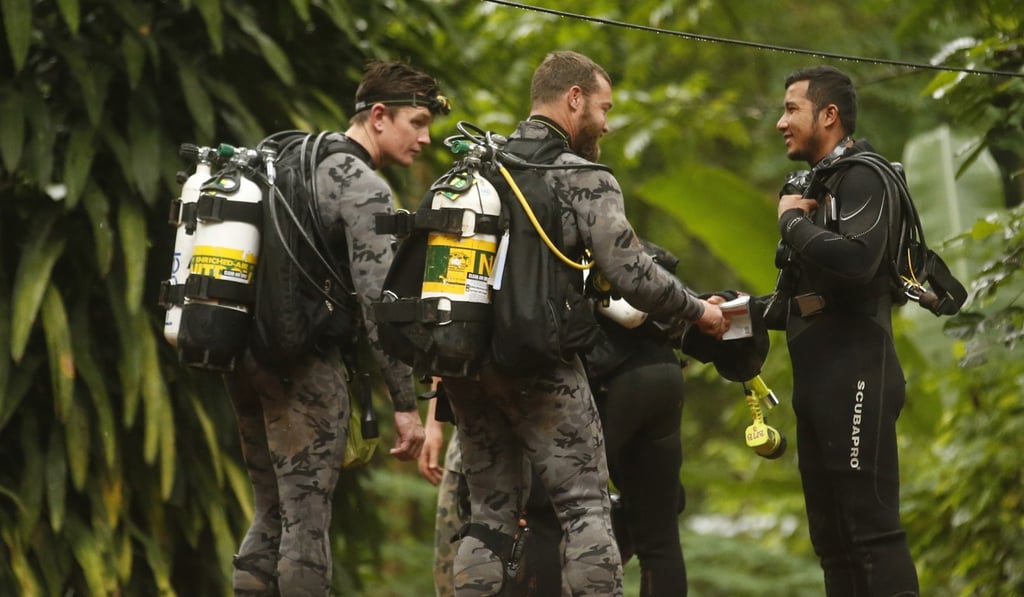 Australian divers including Dr Richard Harris (centre) talk with a Thai diver outside the flooded cave. Photo: AP Australian divers including Dr Richard Harris (centre) talk with a Thai diver outside the flooded cave. Photo: AP
