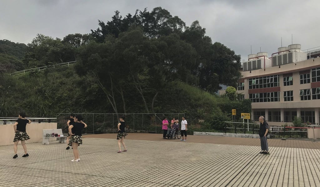 Several seniors look on as women dance outside Yee Hong Heights in Shenzhen. Photo: Kimmy Chung