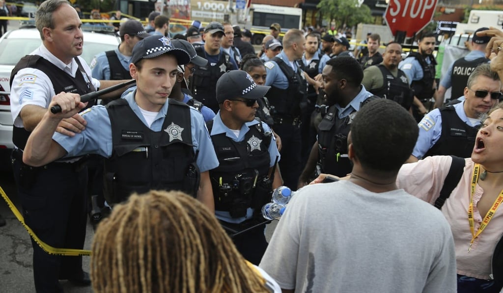 Police interact with an angry crowd at the scene of the shooting in Chicago. Photo: AP