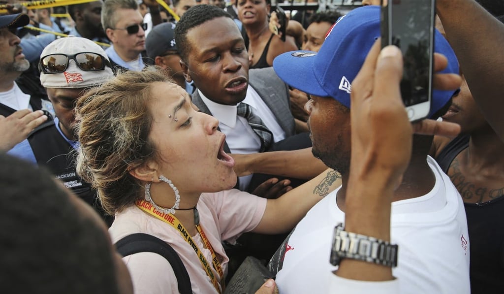 A woman tries to calm a man down as he yells at a police officer. Photo: AP