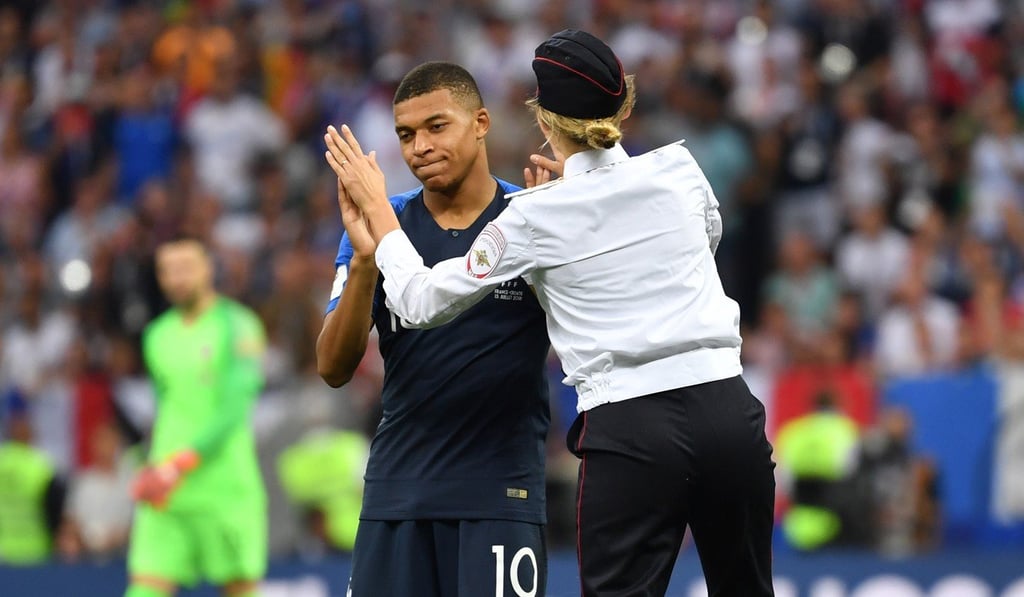 French soccer player Kylian Mbappe high-fives one of the Pussy Riot pitch invaders during the World Cup final at Luzhniki Stadium. Photo: AFP