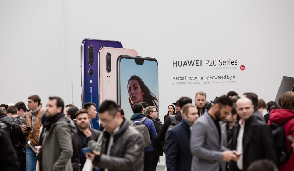 Attendees stand in front of Huawei Technologies Co. signage during the company's P20 Pro smartphone unveiling event in Paris, France, on Tuesday, March 27, 2018. Huawei is launching the P20 as an upgrade to the higher end of its flagship smartphones, walking in the footsteps of rival Samsung Electronics Co. by betting heavily on the camera. Photographer: Marlene Awaad/Bloomberg