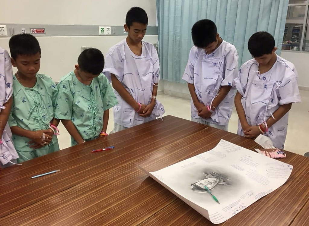 Members of the ‘Wild Boars’ soccer team pay their respects after signing a picture of Samarn Kunan. Photo: Chiang Rai Prachanukroh Hospital and Ministry of Public Health handout via Reuters