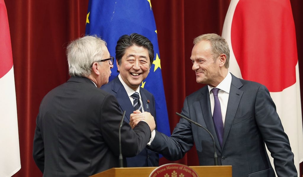 Japanese Prime Minister Shinzo Abe smiles as European Council President Donald Tusk and European Commission President Jean-Claude Juncker shake hands after signing a free trade deal with Japan. Photo: Kyodo