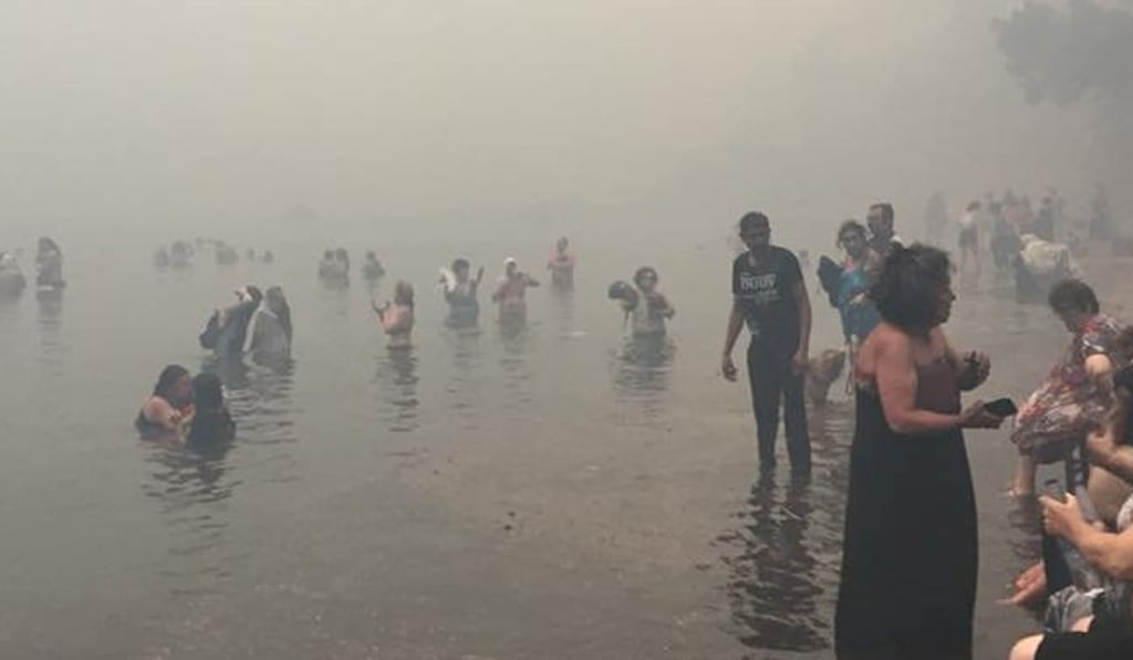 People take refuge in the sea as a wildfire burns in Mati, Greece, on Monday in this picture obtained from social media. Photo: Nikos Kalogerikos via Reuters
