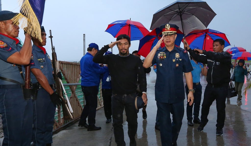 Philippine boxing icon Manny Pacquiao salutes during an arrival honours after returning to his native Philippines from Malaysia. Photo: AFP