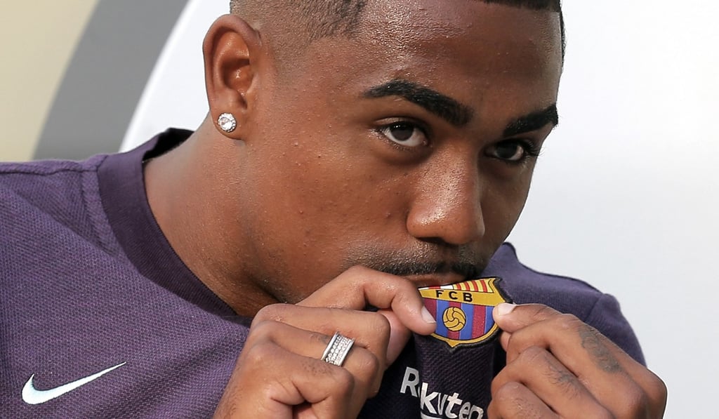 Malcom, kissing the Barcelona badge on his shirt, will join up with his new teammates on their US tour. Photo: AP Malcom, kissing the Barcelona badge on his shirt, will join up with his new teammates on their US tour. Photo: AP