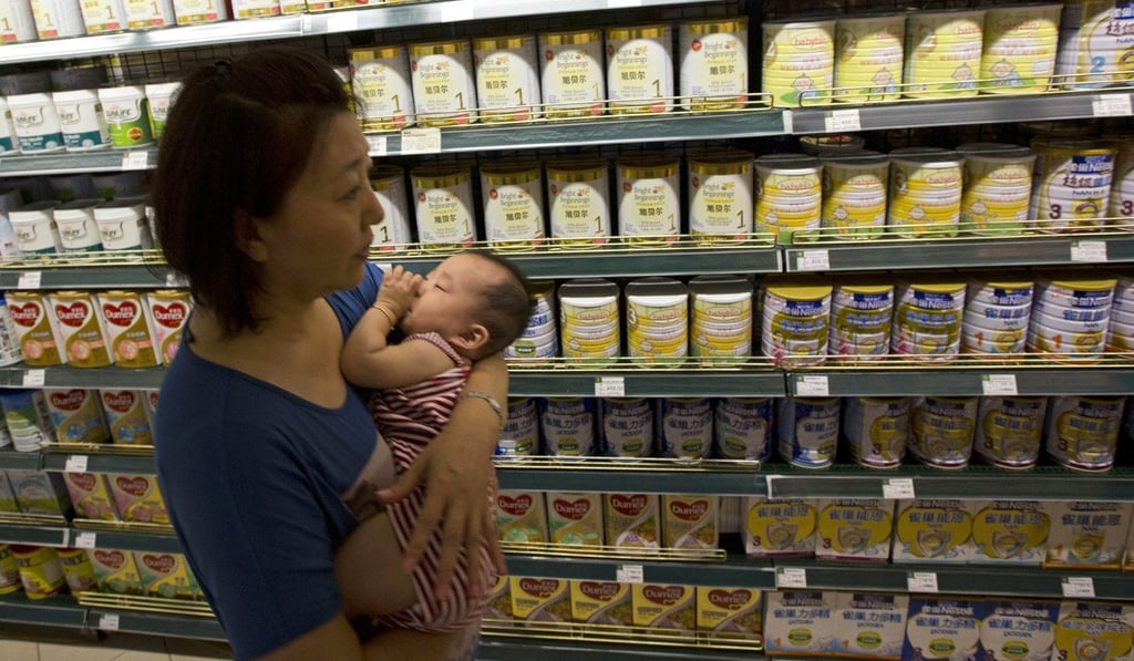 A woman carries a child past powdered milk products at a supermarket in Beijing. Photo: AP