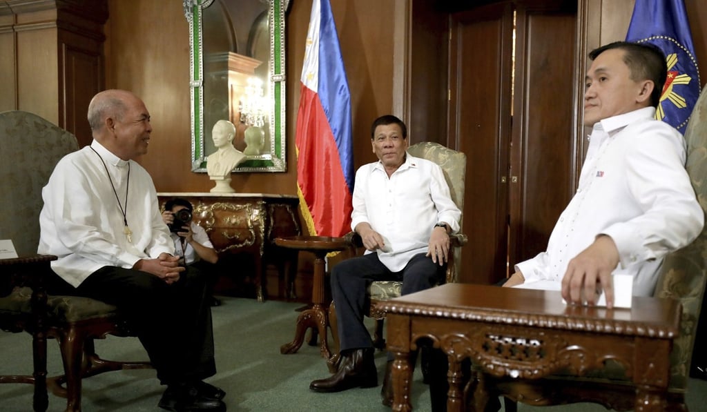 Rodrigo Duterte, centre, meets with the Archbishop of Davao Romulo Valles, left, after the president called God “stupid” and questioned God's existence in profane remarks. Photo: AP Rodrigo Duterte, centre, meets with the Archbishop of Davao Romulo Valles, left, after the president called God “stupid” and questioned God's existence in profane remarks. Photo: AP