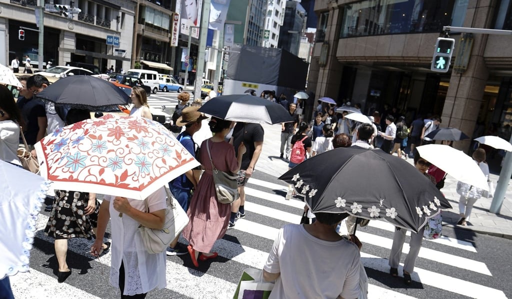 People under parasols walking on a pedestrian crossing in Tokyo during the July heatwave. Photo: AP