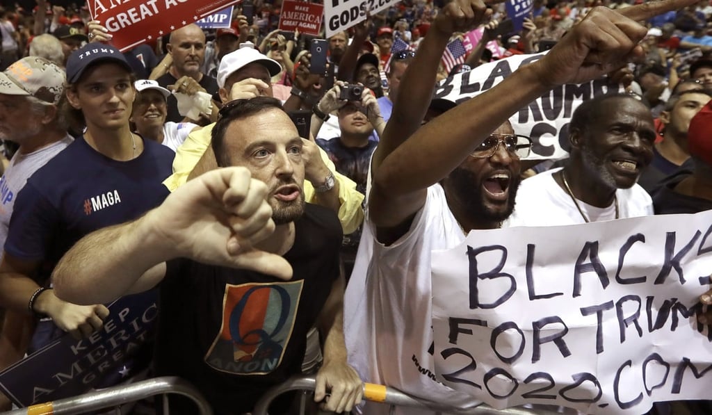 Supporters of President Donald Trump shout down a CNN news crew before a rally in Tampa, Florida, on Tuesday. The man on the left wears a “Q” logo on his shirt. Photo AP