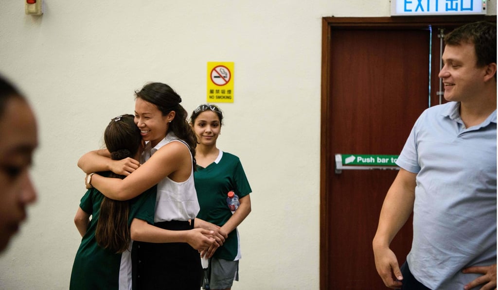 Syrian squash player Sabah Husryeh (second left) is hugged by Rachel Lee, vice president of Squash Dreamers, after her match against Tang Nga Man of Hong Kong (left). Photo: AFP