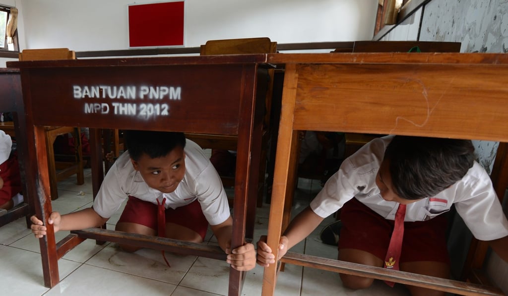 Schoolchildren take cover under tables during a tsunami drill in Tanjung Benoa near Denpasar, Bali. Photo: AFP