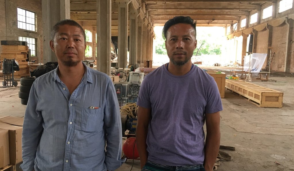 Xia Xiang (left) and another of Ai Weiwei’s assistants, Garang, at the artist’s studio, a former factory on the outskirts of Beijing. Packing cases for Ai artworks stored there can be seen behind them. Photo: Elaine Yau