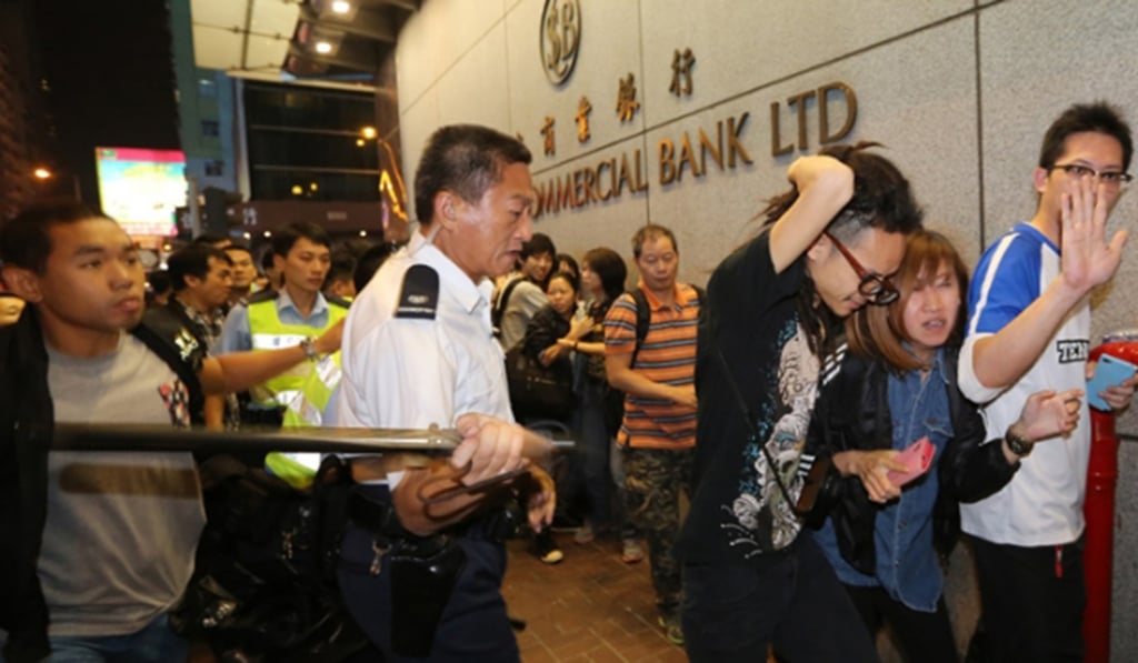 Police commander Franklin Chu uses a baton to hit a pedestrian in Mong Kok. Photo: Handout