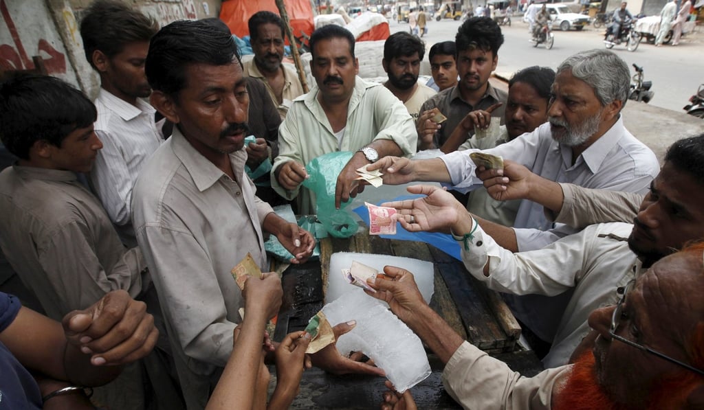 A vendor in Karachi sells blocks of ice to people eager to beat the heat. Photo: Reuters