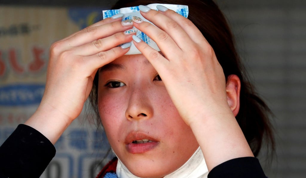 A volunteer recovery worker uses a pack of refrigerant to cool down at a flood affected area in Kurashiki, Okayama Prefecture, Japan. Photo: Reuters