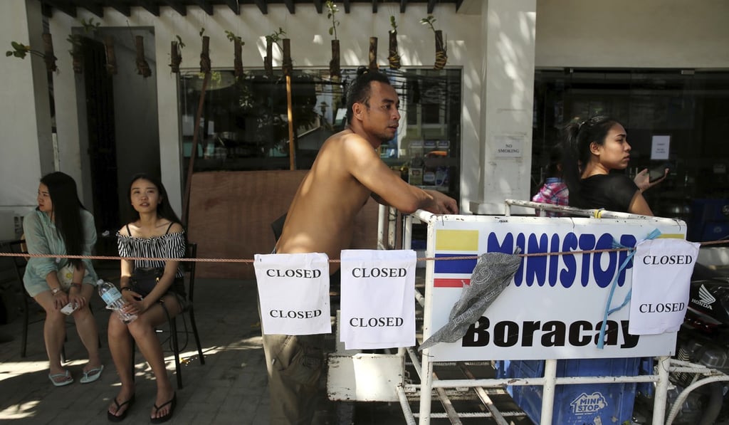 A worker waits outside a closed shop on Boracay. Only businesses found to be compliant with new environmental and legal requirements will be allowed to operate when the island reopens in October.