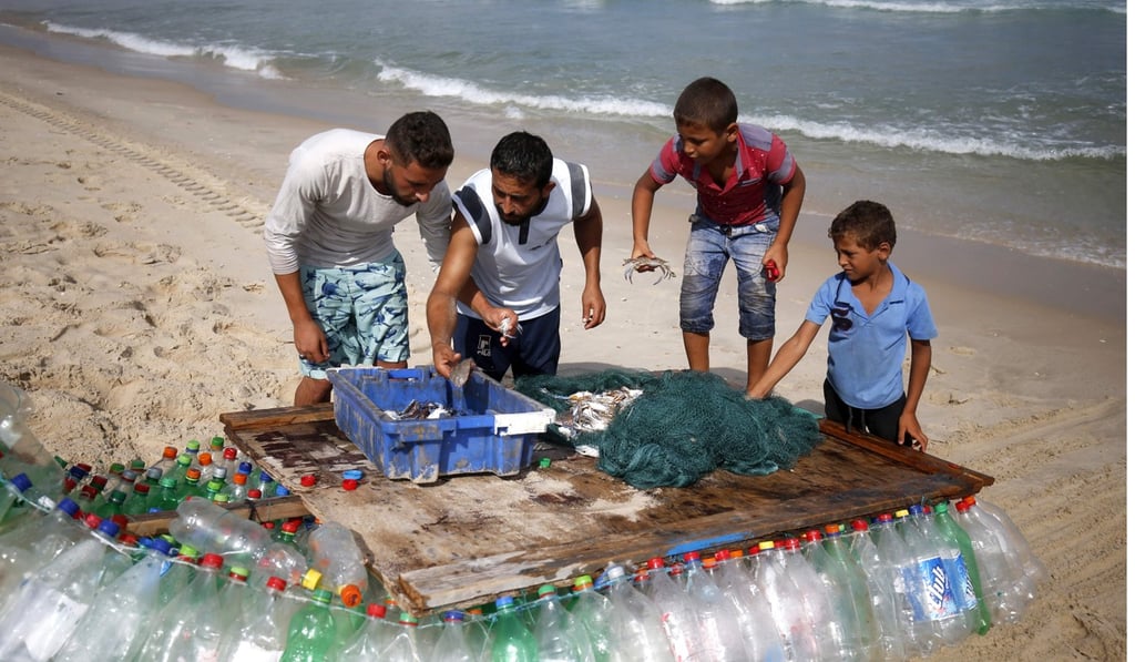 Palestinian fisherman Muath Abu Zeid (second left) sorts his catch on the beach at Rafah in the southern Gaza Strip. He catches about seven or eight kilograms of fish per day. Photo: Agence France-Presse Palestinian fisherman Muath Abu Zeid (second left) sorts his catch on the beach at Rafah in the southern Gaza Strip. He catches about seven or eight kilograms of fish per day. Photo: Agence France-Presse