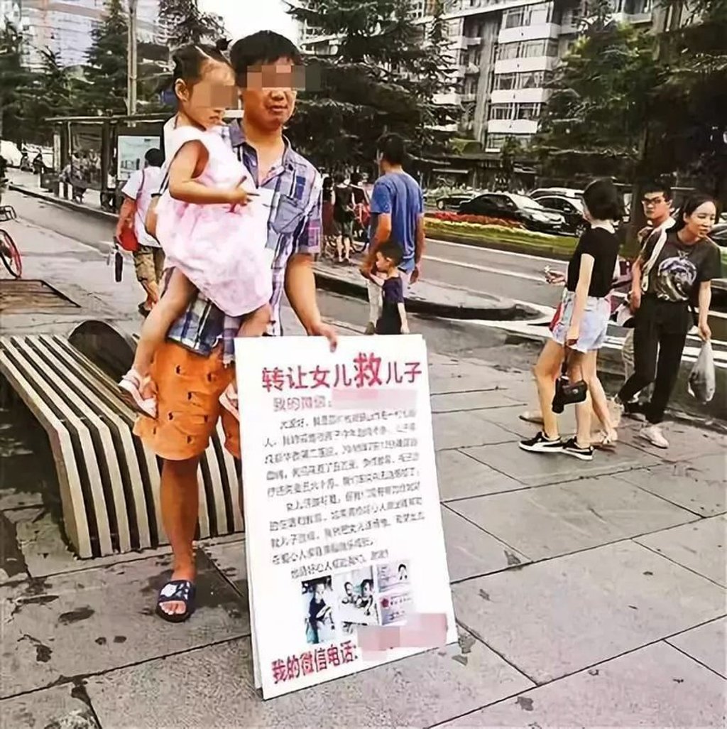 Liang took to the streets with a placard seemingly offering his four-year-old daughter for sale. Photo: news.ifeng.com