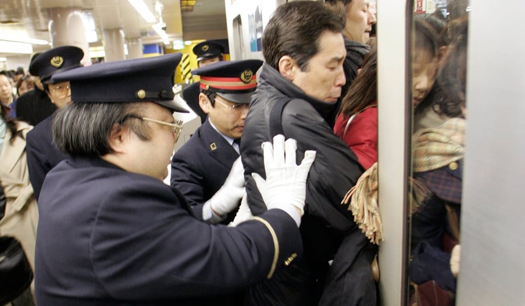 Staff push a passenger into a crowded subway train at the Ikebukuro station on the Marunouchi line during rush hour in Tokyo. Photo: Reuters